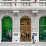 A Versace storefront with green-lit arched display windows on a marble facade