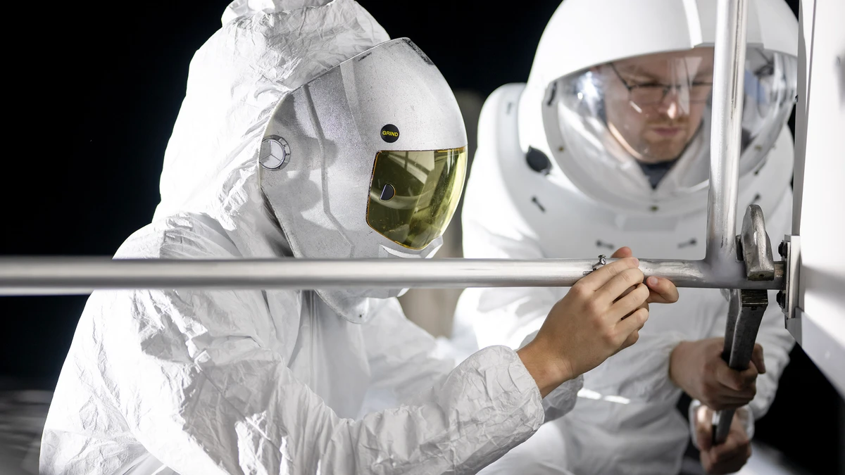 Two suited engineers work under harsh directional lighting during a NASA lunar surface lighting simulation for Artemis III