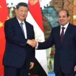 Xi Jinping shakes hands with Abdel Fattah el-Sisi in front of the Chinese and Egyptian flags in Cairo