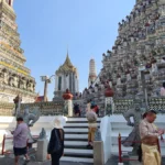 Visitors climbing the steps of Wat Arun temple in Bangkok, Thailand