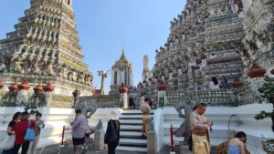 Visitors climbing the steps of Wat Arun temple in Bangkok, Thailand