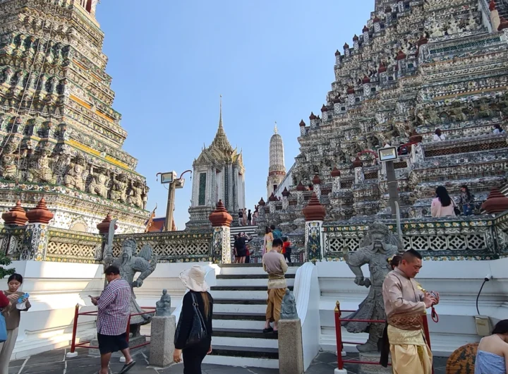 Visitors climbing the steps of Wat Arun temple in Bangkok, Thailand